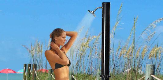 mujer duchándose en una ducha solar negra junto a la playa